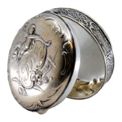 Silver box for rosary in circular shape with scrolls, flowers and angel figure