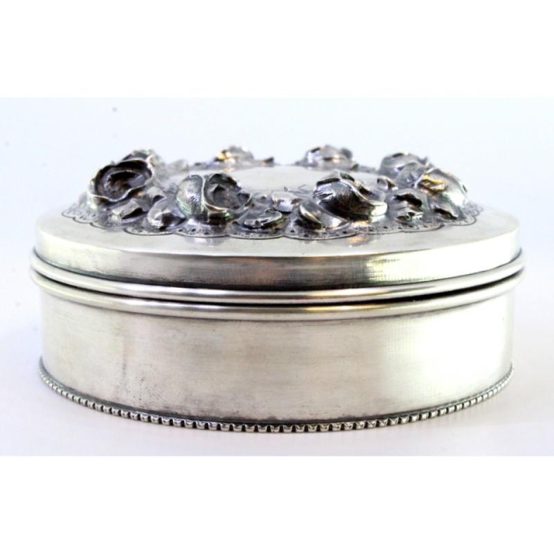 Silver box w/ raised floral motifs & a surrounding frieze on the circular base For Sale 1