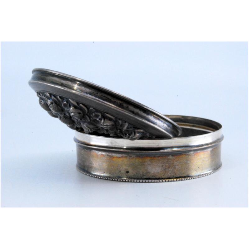 Description: Silver box with embossed flowers on the lid and pearl trim. Metal: Silver. Origin: Portuguese. Brand: Eagle Head. Weight: 76.18 grams. Dimensions: 8x3cm. Content: 833/1000. Assay Mark: Yes, between 1938 and 1984. Additional information:
