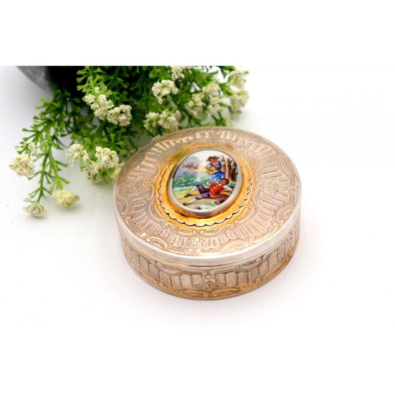 Description: Silver box with reliefs and an idyllic scene on enamels on the removable lid. Metal: Silver. Origin: Portuguese. Mark: open-winged eagle. Weight: 187.02 gr. Dimensions: 9.5cmx9.5cm. Content: 833/1000. Assay Mark: Yes, between 1937 and