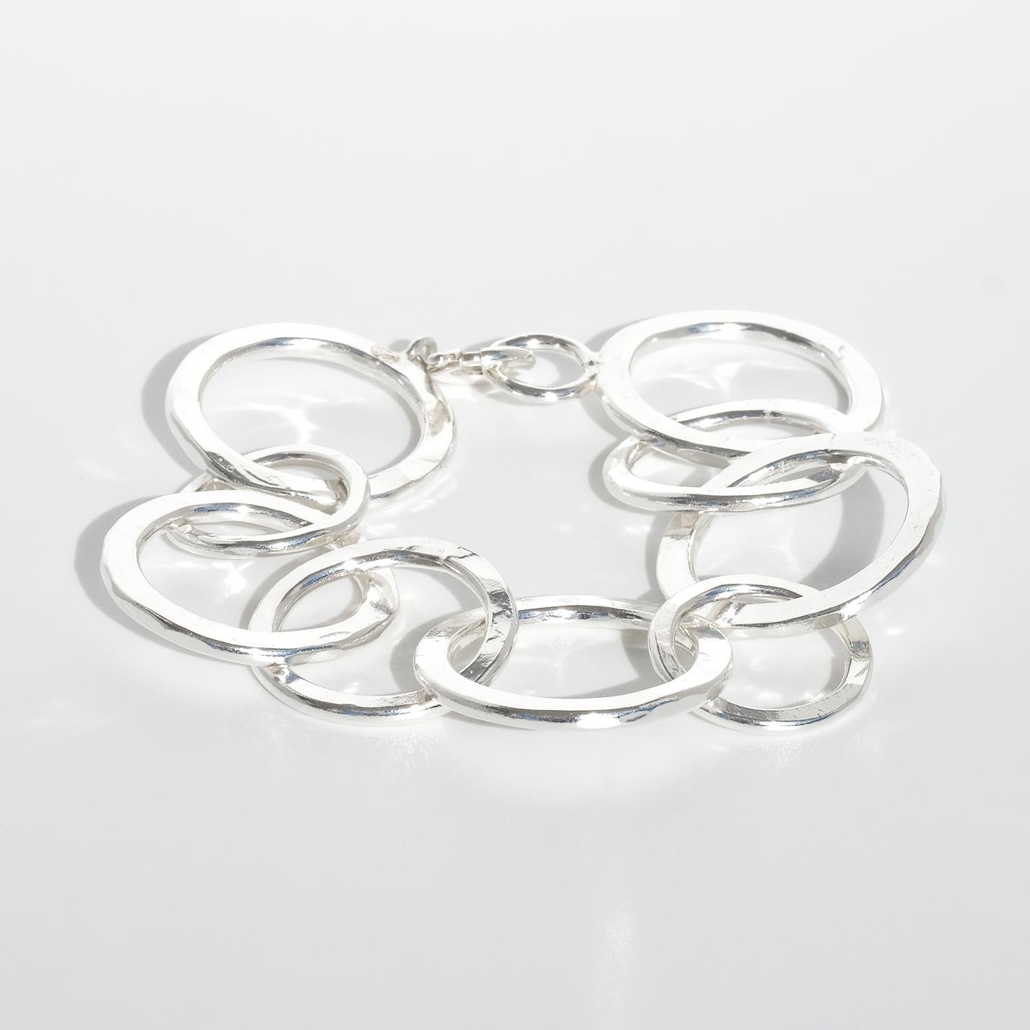 Esta pulsera de plata presenta una serie de círculos entrelazados de distintos tamaños, creando un diseño atrevido y contemporáneo. El acabado pulido añade un toque elegante y liso, mientras que la estructura circular interconectada proporciona