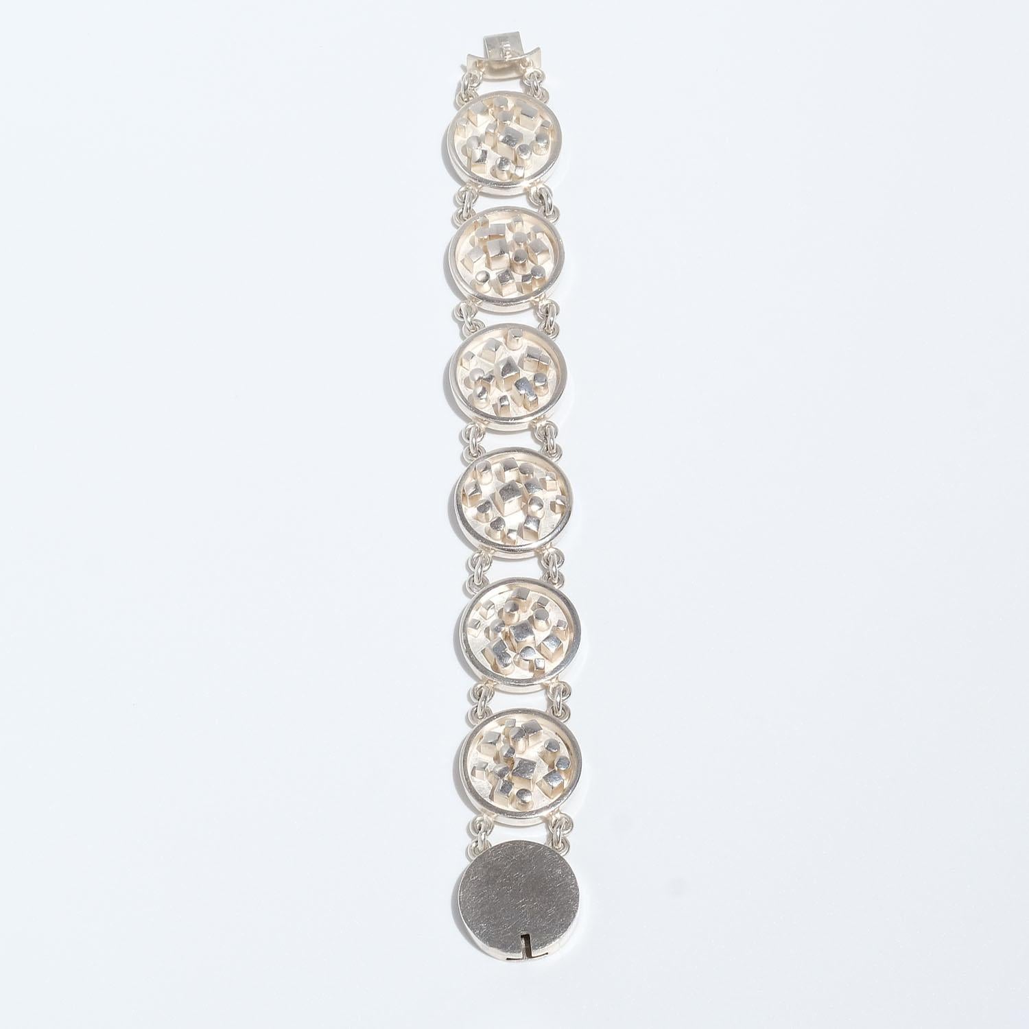 This silver bracelet is made out of six round links which are linked together. Each link is decorated with a geometric relief pattern. The bracelet closes easily with a box clasp.

The design of the bracelet is making it slide beautifully down its