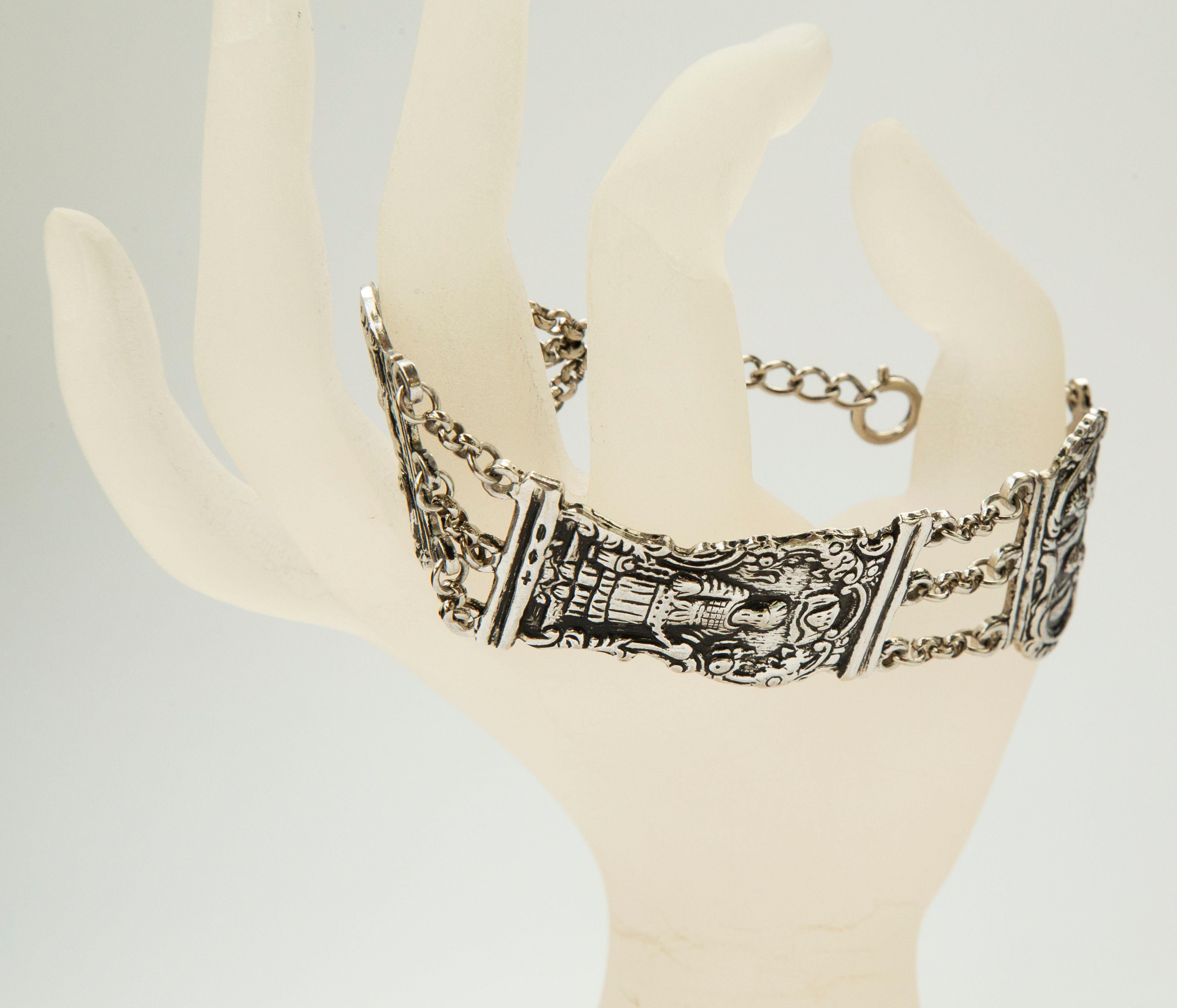 Un bracelet en argent fait d'une fermeture bible antique créée dans les années 1700/1800. Les maillons libres du bracelet représentent différentes figures bibliques sur un fond floral et sont reliés entre eux par une chaîne à trois rangs. Le