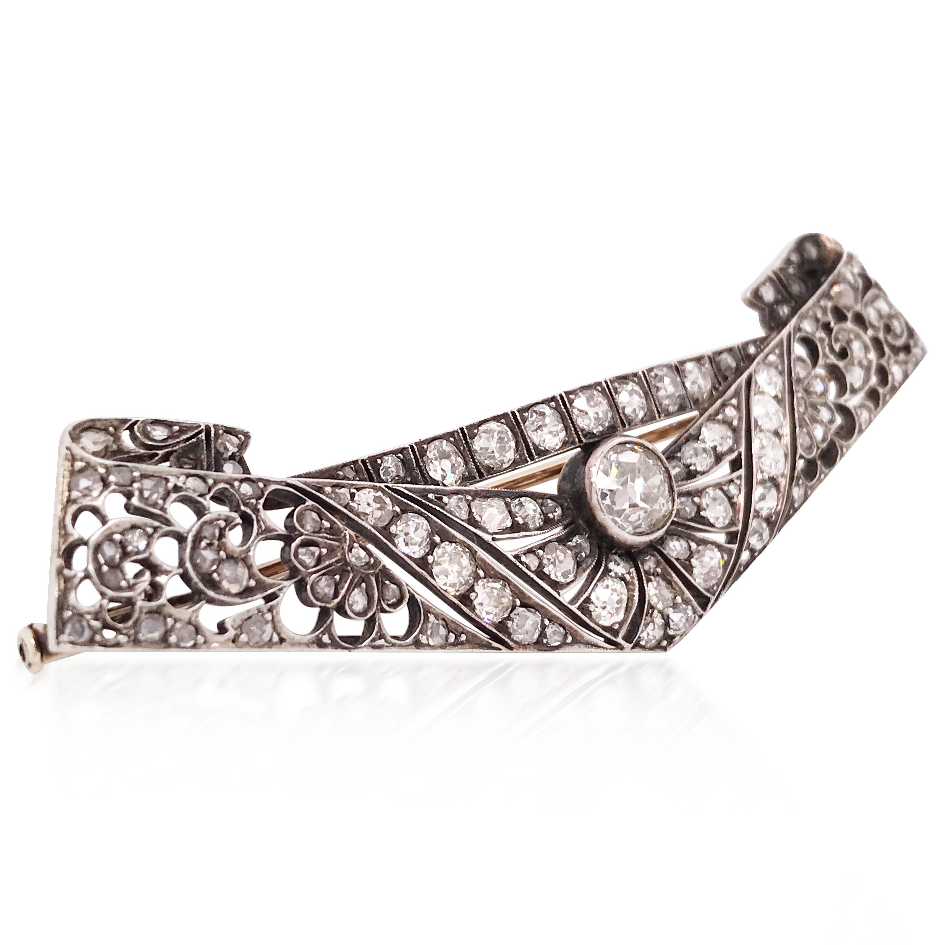Silver brooch in a quadrangular shape, cut with interlocking geometric patterns and stylized feathers set with antique cut diamonds, cut in roses, centered with a larger round diamond. Circa 1920s.

Measurement: length 7cm
Weight: 10.3 grams