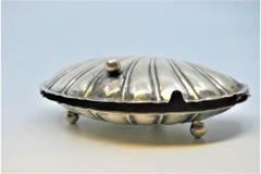 Silver butter dish in the shape of a double shell and resting on three feet