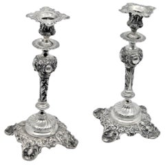 Silver candlesticks embossed w/ floral motifs 
scrolls, sconces 
cut-out bases