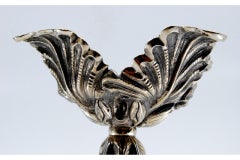 Silver candlesticks embossed with acanthus leaves and resting on three feet