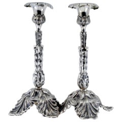 Silver candlesticks embossed with acanthus leaves and resting on three feet