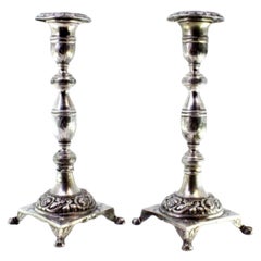 Silver candlesticks with engraved shafts on floral bases with claw feet