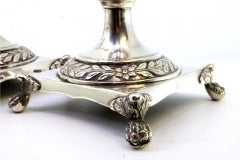 Silver candlesticks with engraved stems and four claw feet on square bases