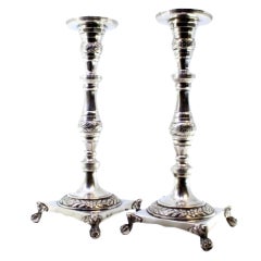 Silver candlesticks with engraved stems and four claw feet on square bases