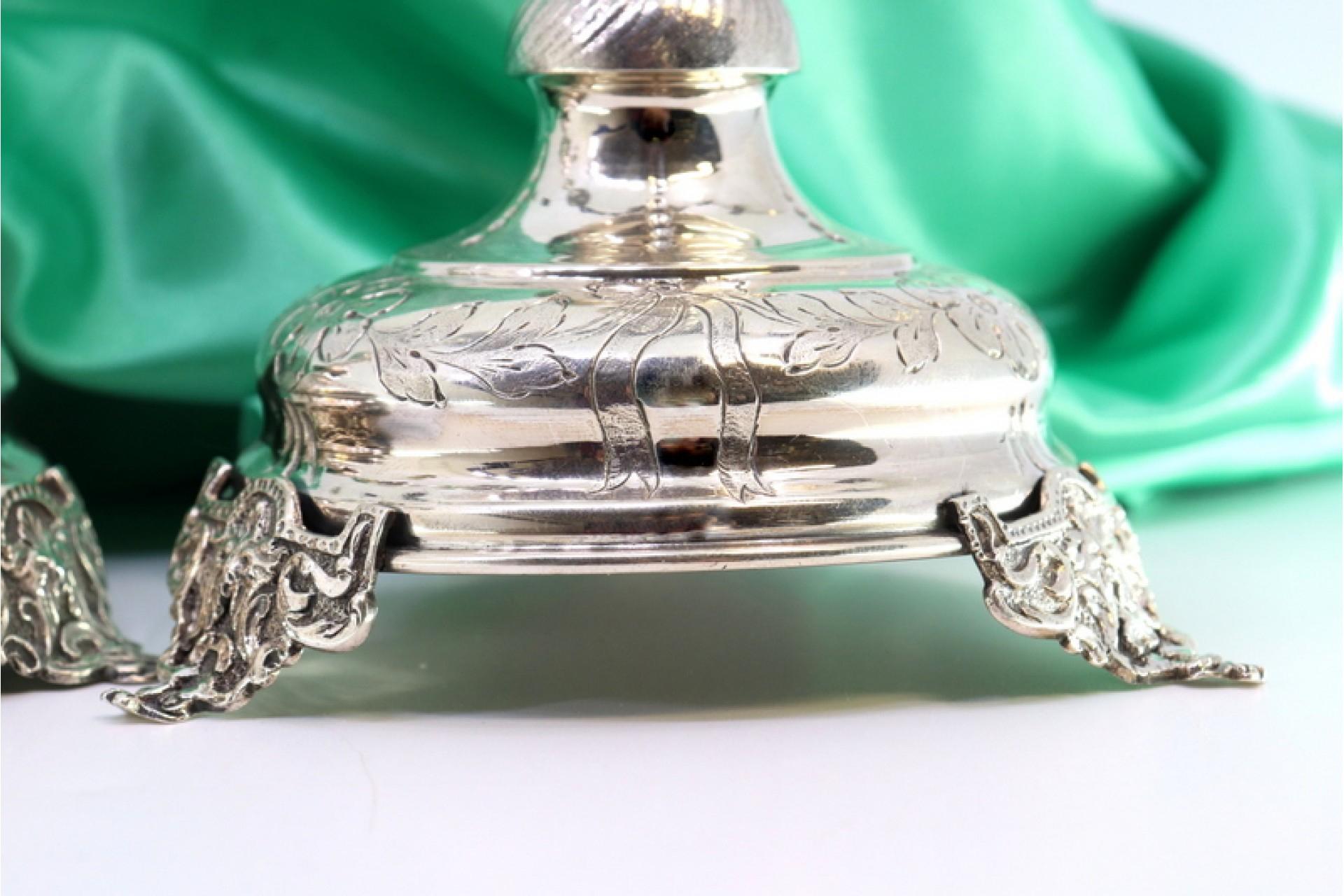 Description: Silver candlesticks with engraved floral motifs, circular bases and resting on three raised feet. Metal: Silver. Origin: Portuguese. Brand: javali II Title. Weight: 341.66 grams. Dimensions: 12cmx24cm. Content: 833/1000. Assay Mark: