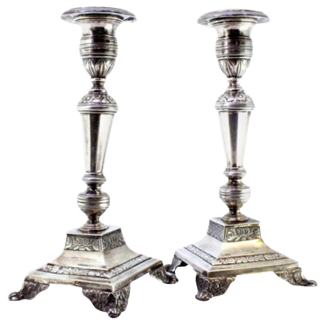 Silver candlesticks with floral engravings on raised square bases with four feet