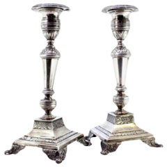 Silver candlesticks with floral engravings on raised square bases with four feet
