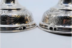 Silver candlesticks with floral engravings on sconces, shafts and circular bases