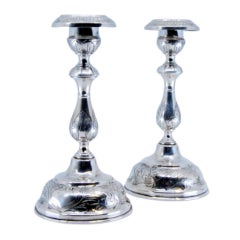 Silver candlesticks with floral engravings on sconces, shafts and circular bases