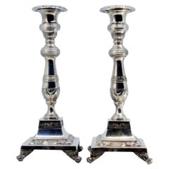 Silver candlesticks with floral engravings on square bases with round feet
