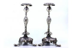 Silver candlesticks with floral reliefs and acanthus-shaped tripod bases