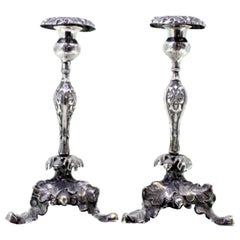 Silver candlesticks with floral reliefs and acanthus-shaped tripod bases