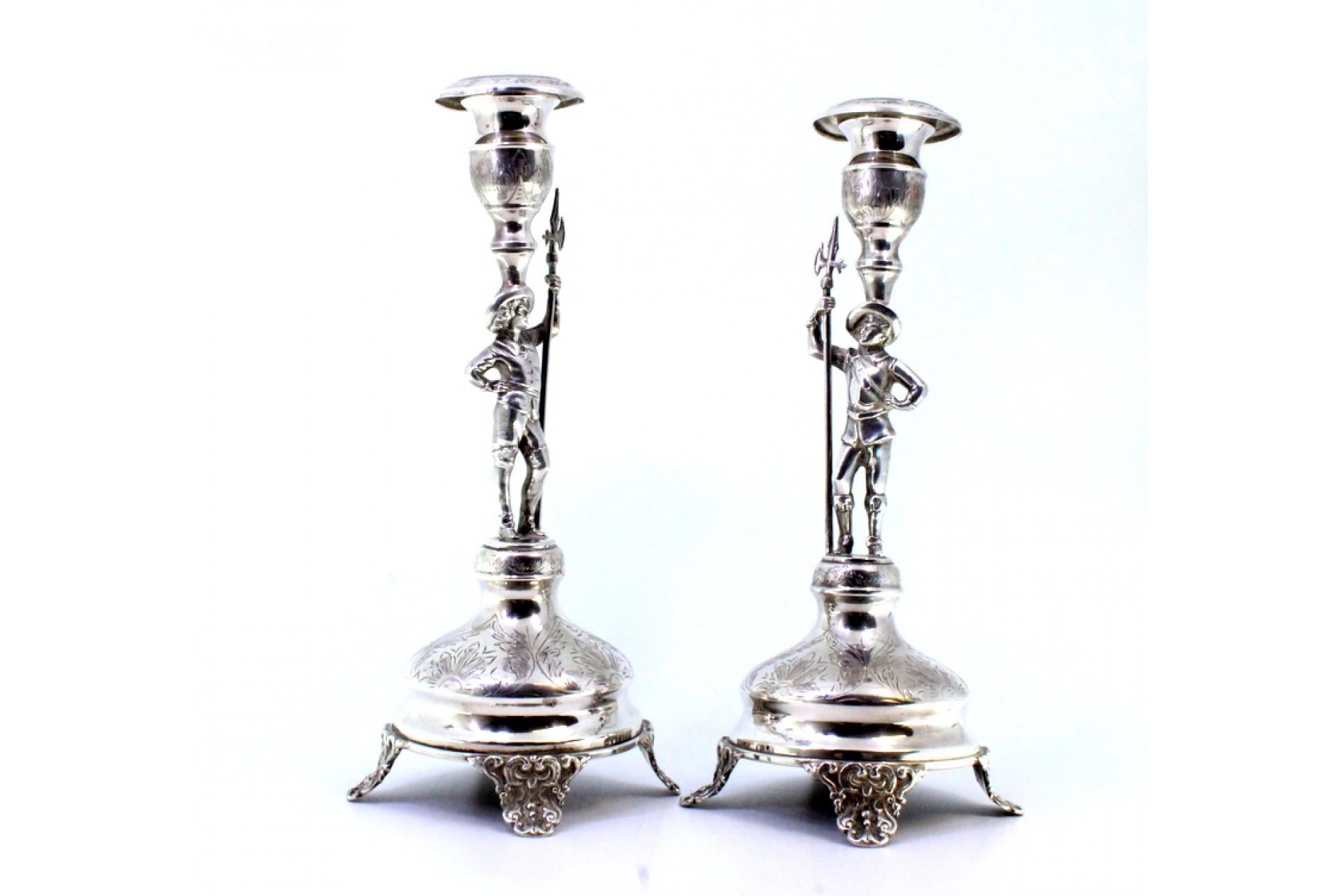 Description: Set of silver candlesticks with halberdiers on a pedestal, engraved plant elements and resting on four embossed feet. Metal: Silver. Origin: Portuguese. Brand: Eagle Head. Weight: 882.79 grams (Set of Candlesticks). Dimensions:
