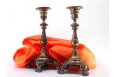 Silver candlesticks with relief stems and four claw feet on square bases
