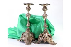 Silver candlesticks with stems and tripod bases cut with reliefs