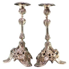 Silver candlesticks with stems and tripod bases cut with reliefs