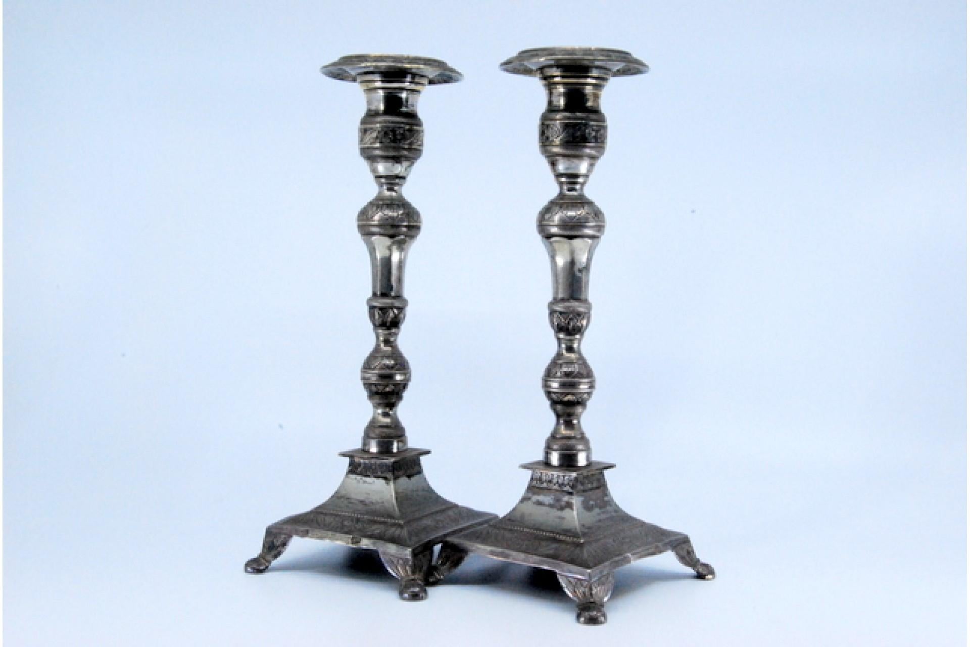 Description: Silver candlesticks with turned and embossed shafts, resting on square bases with four feet. Metal: Silver. Origin: Portuguese. Brand: Porto Coroa. Weight: 641.98 grams. Dimensions: 20.4x7.7cm. Content: 833/1000. Assay Mark: Yes, from