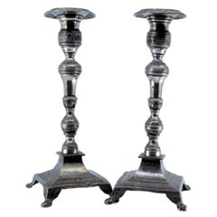 Silver candlesticks with turned embossed shafts on square bases with four legs