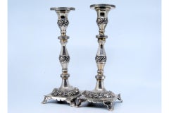Silver candlesticks with turned stems and floral reliefs on four-foot bases