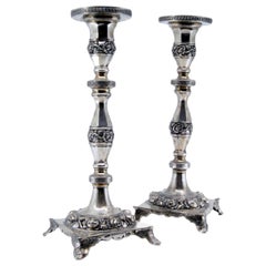 Silver candlesticks with turned stems and floral reliefs on four-foot bases