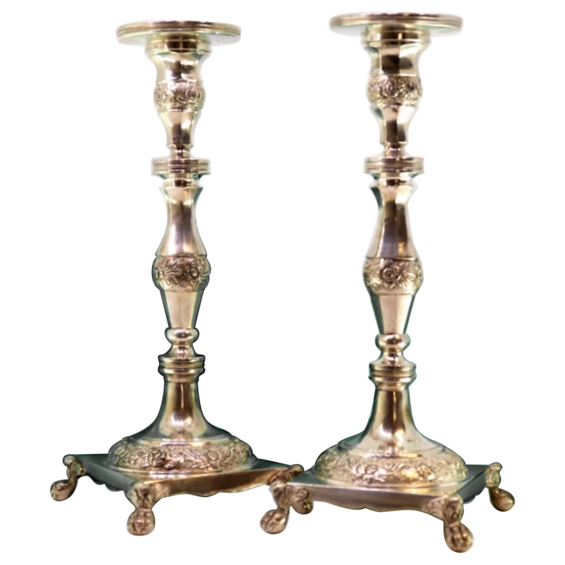 Silver candlesticks with turned stems, floral motifs and claw-foot bases