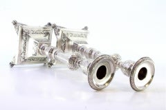 Silver candlesticks with turned stems, sconces and chiseled bases with claw feet