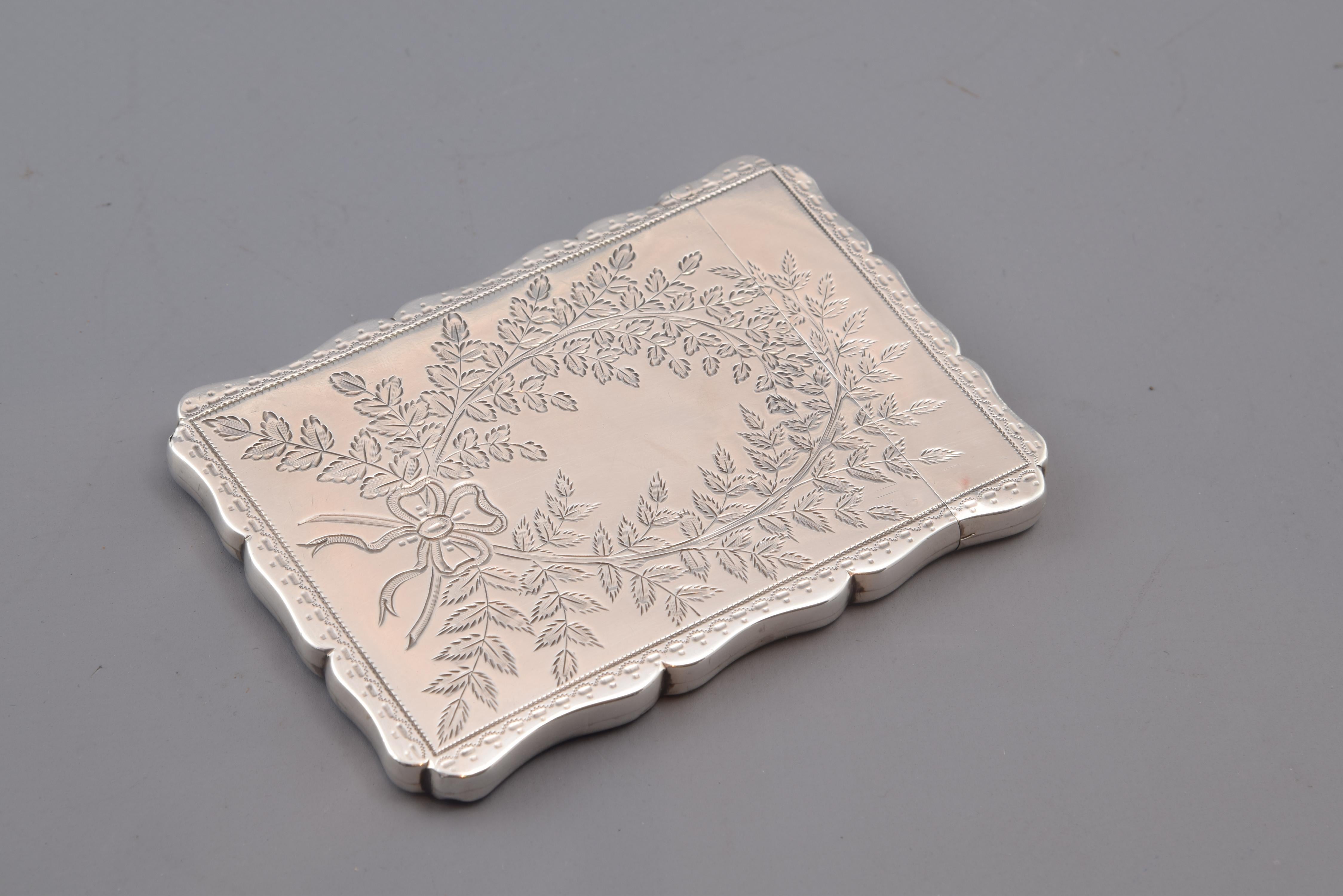 Silver card case, with hallmarks, Robert Thornton, Birmingham, England, 1877.
Card case with opening (hinge) on one of its smaller sides, made of silver in its color and decorated with a wavy edge and plant compositions on the sides (within frames,