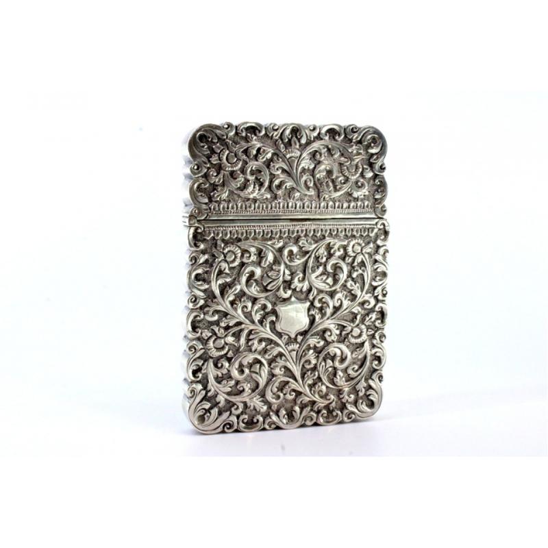 Description: Silver card case with embossed wreaths surrounding a monogram card. Metal: Silver. Origin: European. Mark: Absent. Weight: 123.94 grams. Dimensions: 7cmx10cm. Content: 950/1000. Assay Mark: Absent. Additional information: Good condition.