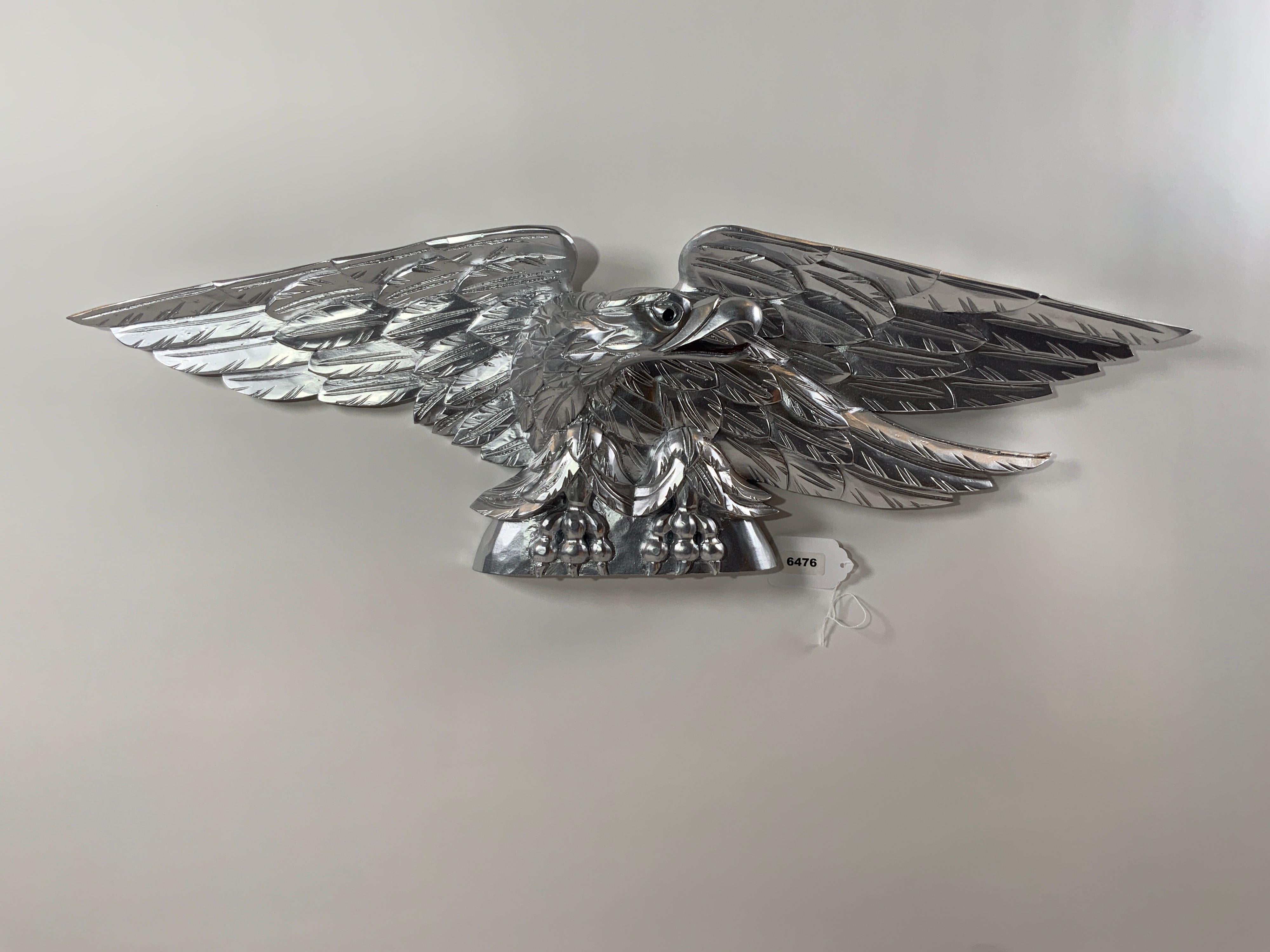 Carved eagle with pediment base. Heavily carved wings. Expertly executed. Flat bottom. Can be displayed on a mantle, over a door, or hung. Silver painted finish.

Overall Dimensions: 11