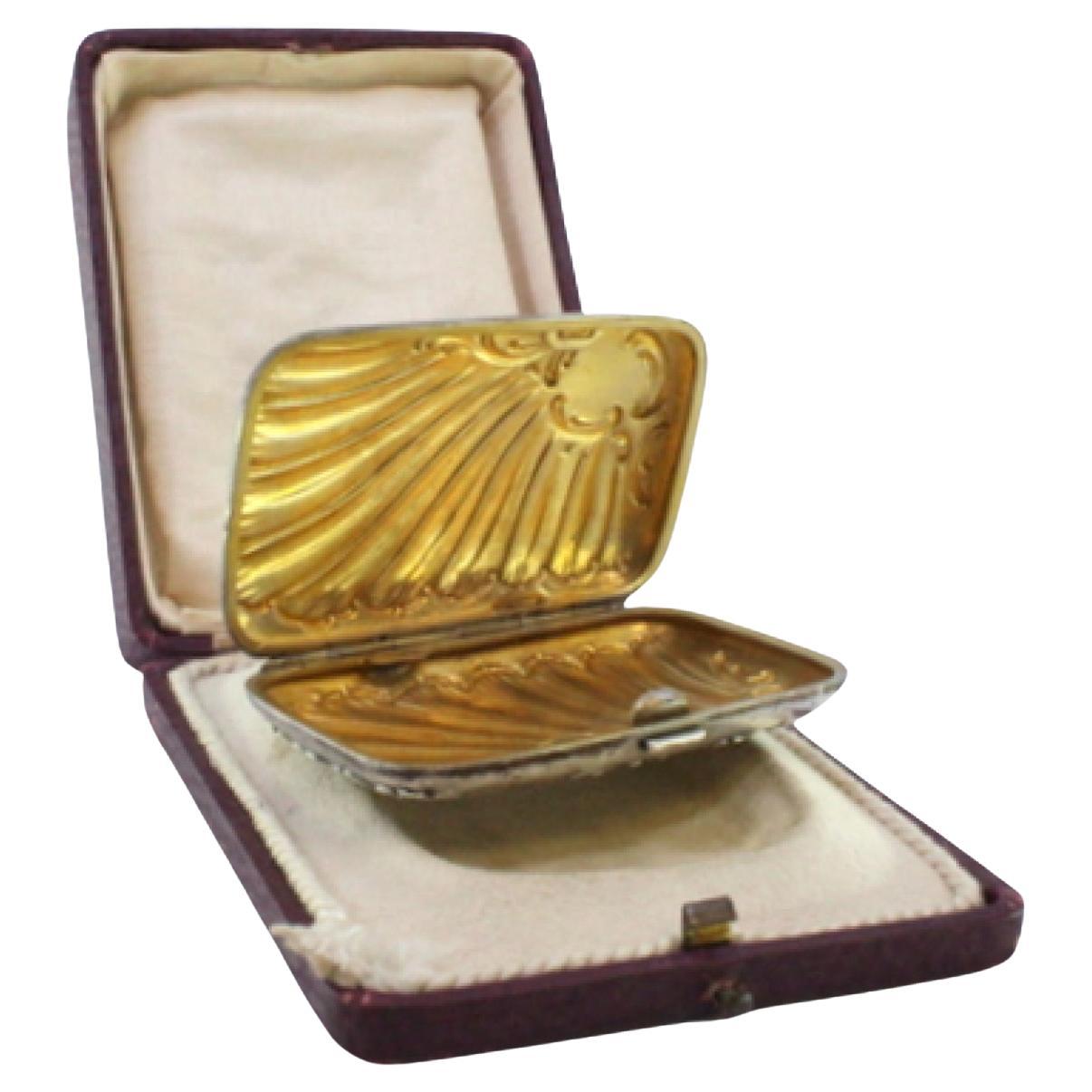 Silver case with Art Nouveau reliefs around monogram and gold interior