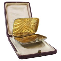 Silver case with Art Nouveau reliefs around monogram and gold interior