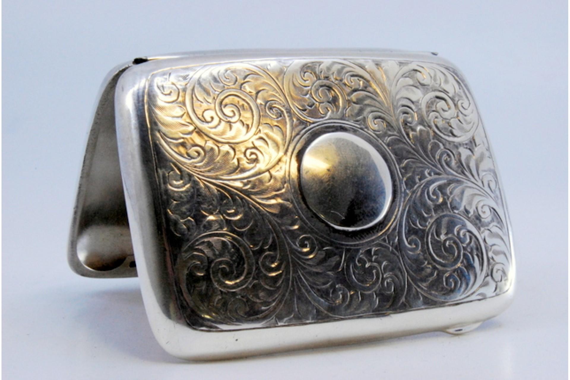 Description: Silver cigarette case with engraved floral motifs surrounding a curved monogram card and hinged lid. Metal: Silver. Origin: English. Brand: Birmingham. Weight: 51.79 grams. Dimensions: 8x6cm. Content: 925/1000. Assay Mark: Yes, 1946.