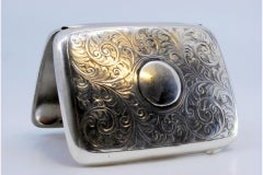 Silbernes Gehäuse mit floralen Gravuren um ein geschwungenes Monogramm und Scharnierdeckel