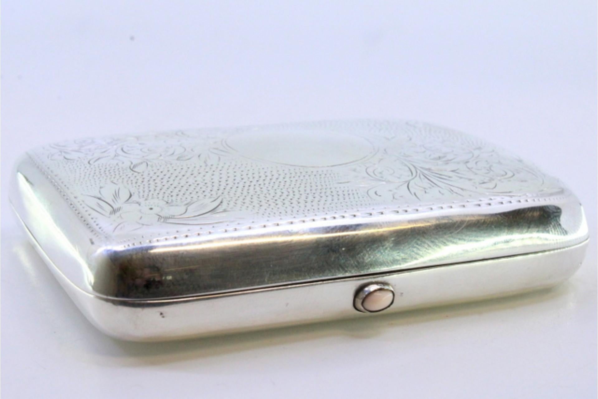 Description: Silver cigarette case with engraved floral motifs surrounding a curved monogram card and spring-hinged lids. Metal: Silver. Origin: English. Brand: Birmingham. Weight: 75.46 grams. Dimensions: 9cmx6.5cm. Content: 925/1000. Assay Mark: