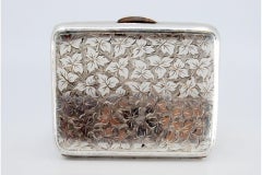 Silver case with floral engravings on both sides, gold interior and hinged lid