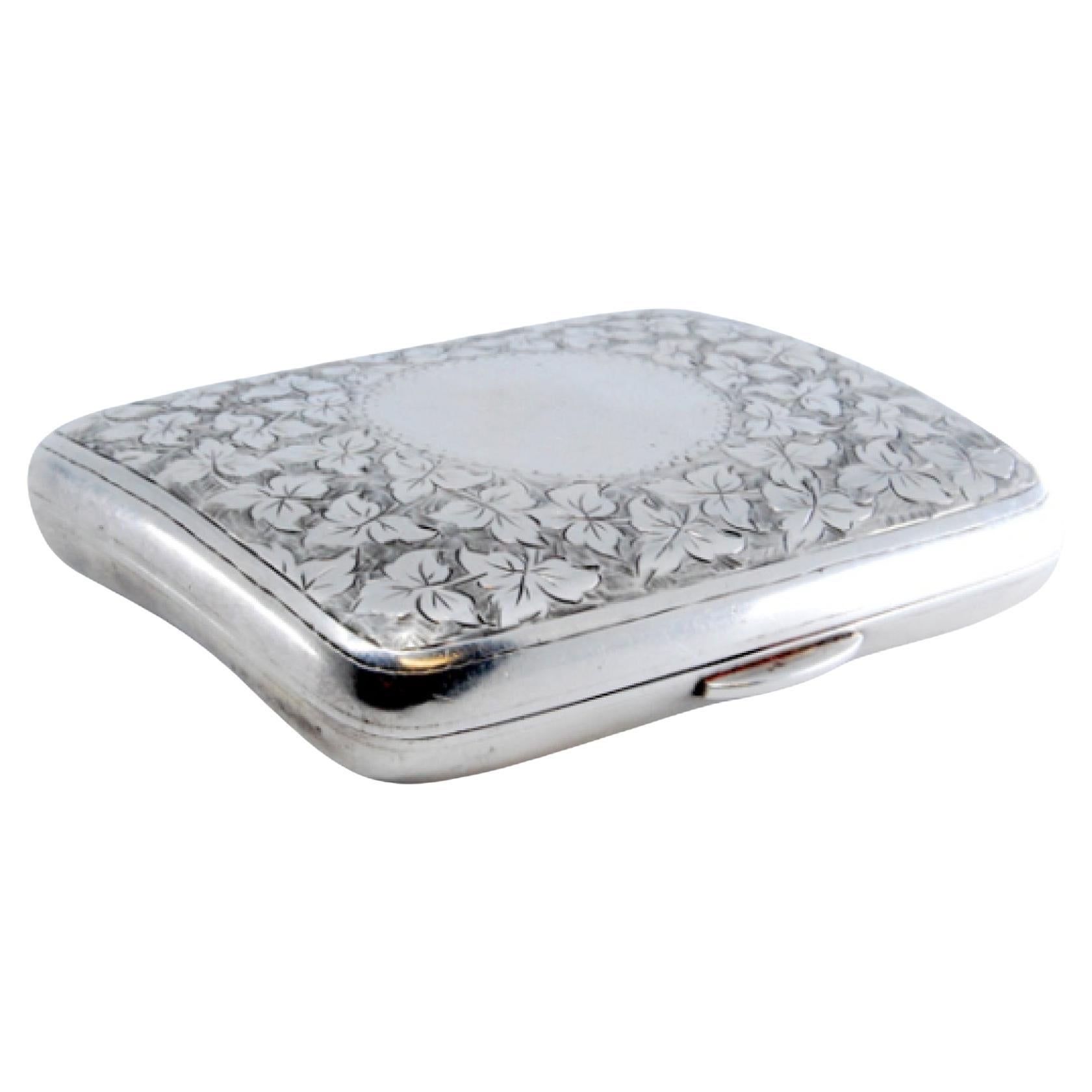 Silver case with floral engravings on both sides, gold interior and hinged lid
