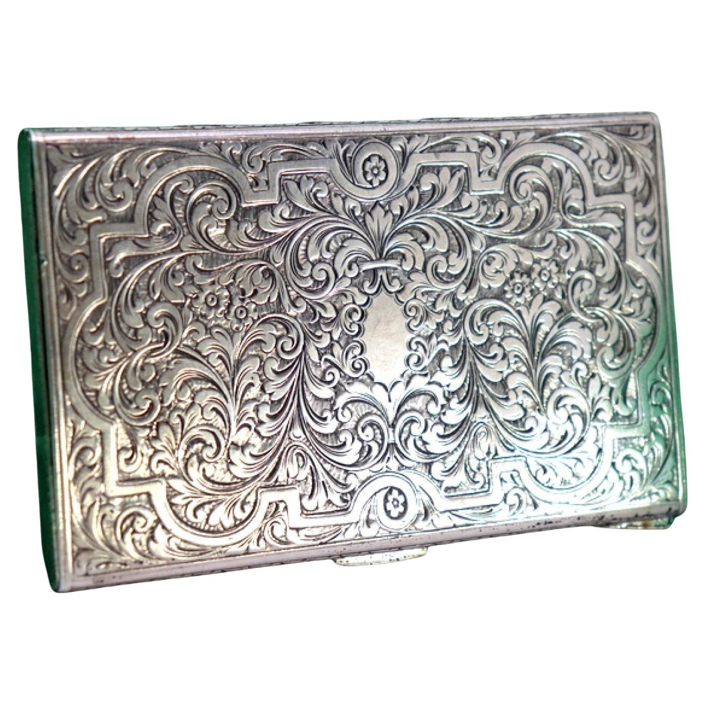 Boîte en argent avec reliefs floraux et fente centrale pour le monogramme, support à l
intérieur.