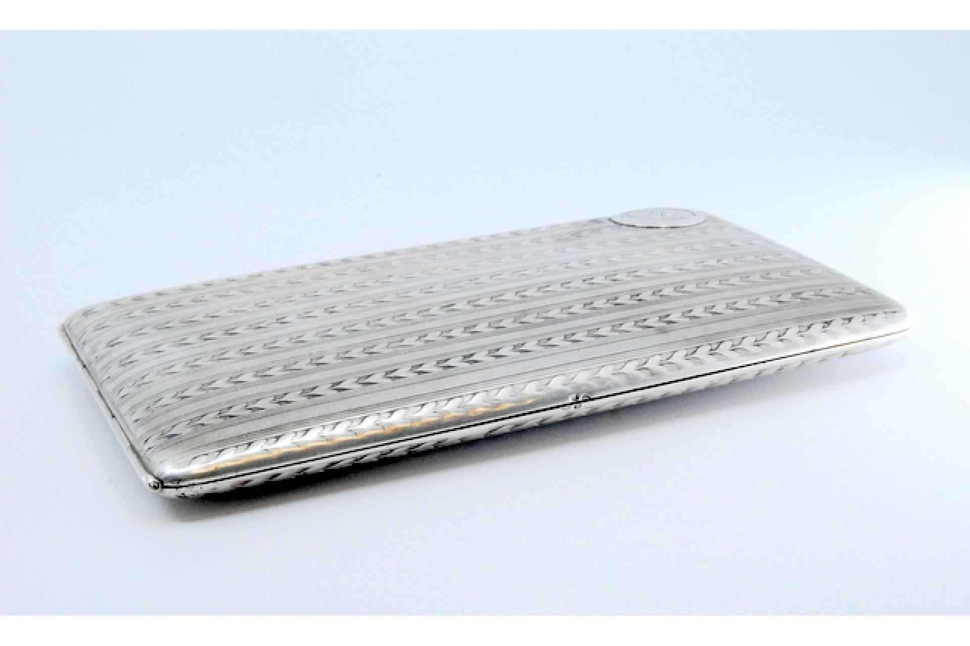 Description: Silver cigarette case with herringbone bands along the length surrounding a monogram card, gold interior and hinged lid. Metal: Silver. Origin: Portuguese. Brand: javali II Title. Weight: 147.63 grams. Dimensions: 14.2x1cm. Content: