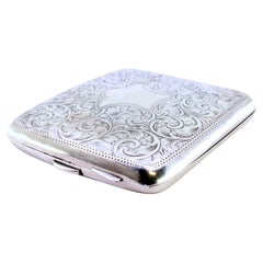 Silver case with plant engravings around curved monogram card