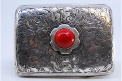 Silver case with plant engravings, red cabochon and curved form