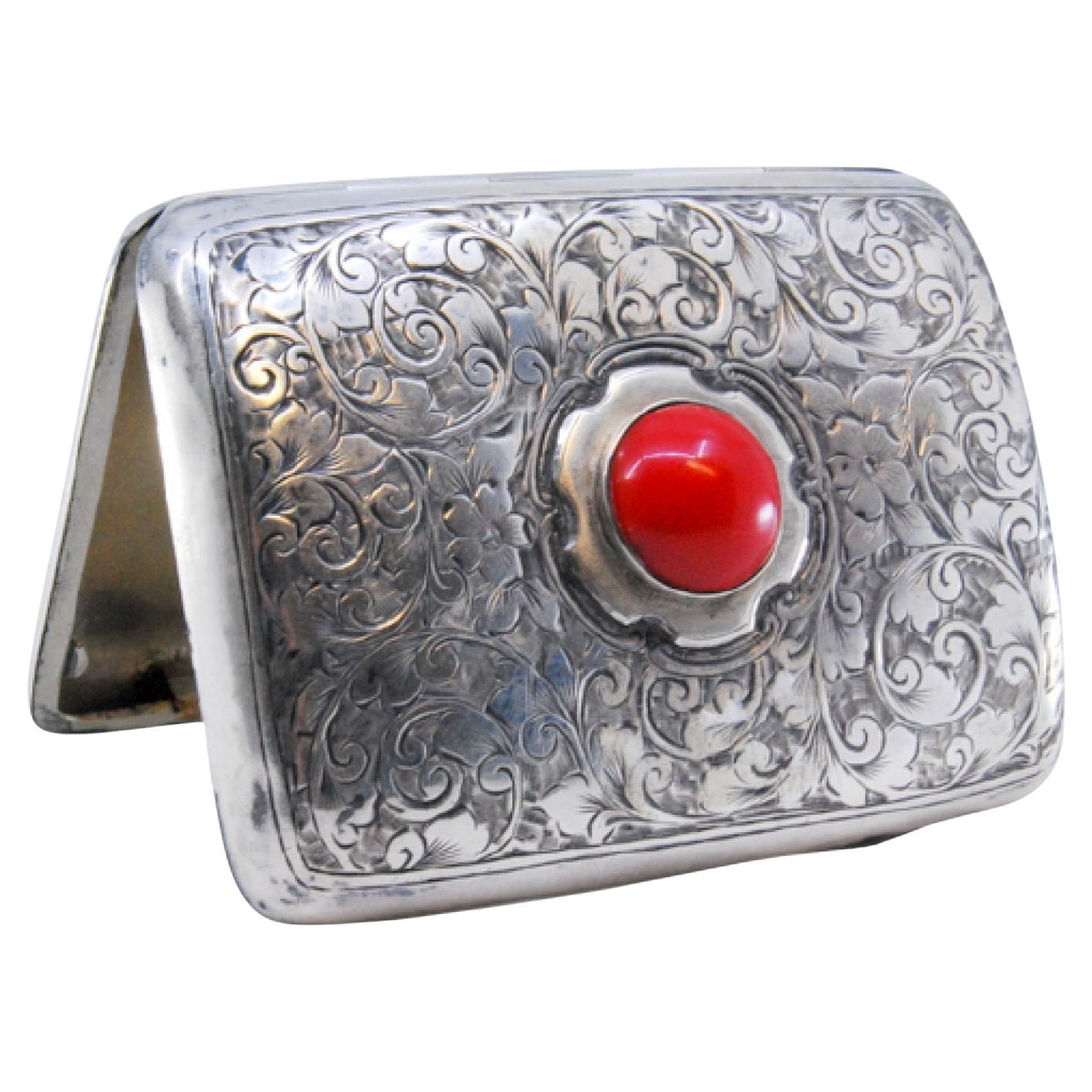Silver case with plant engravings, red cabochon and curved form