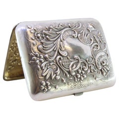 Silver case with raised reliefs and interior monogram in gold with ribbon