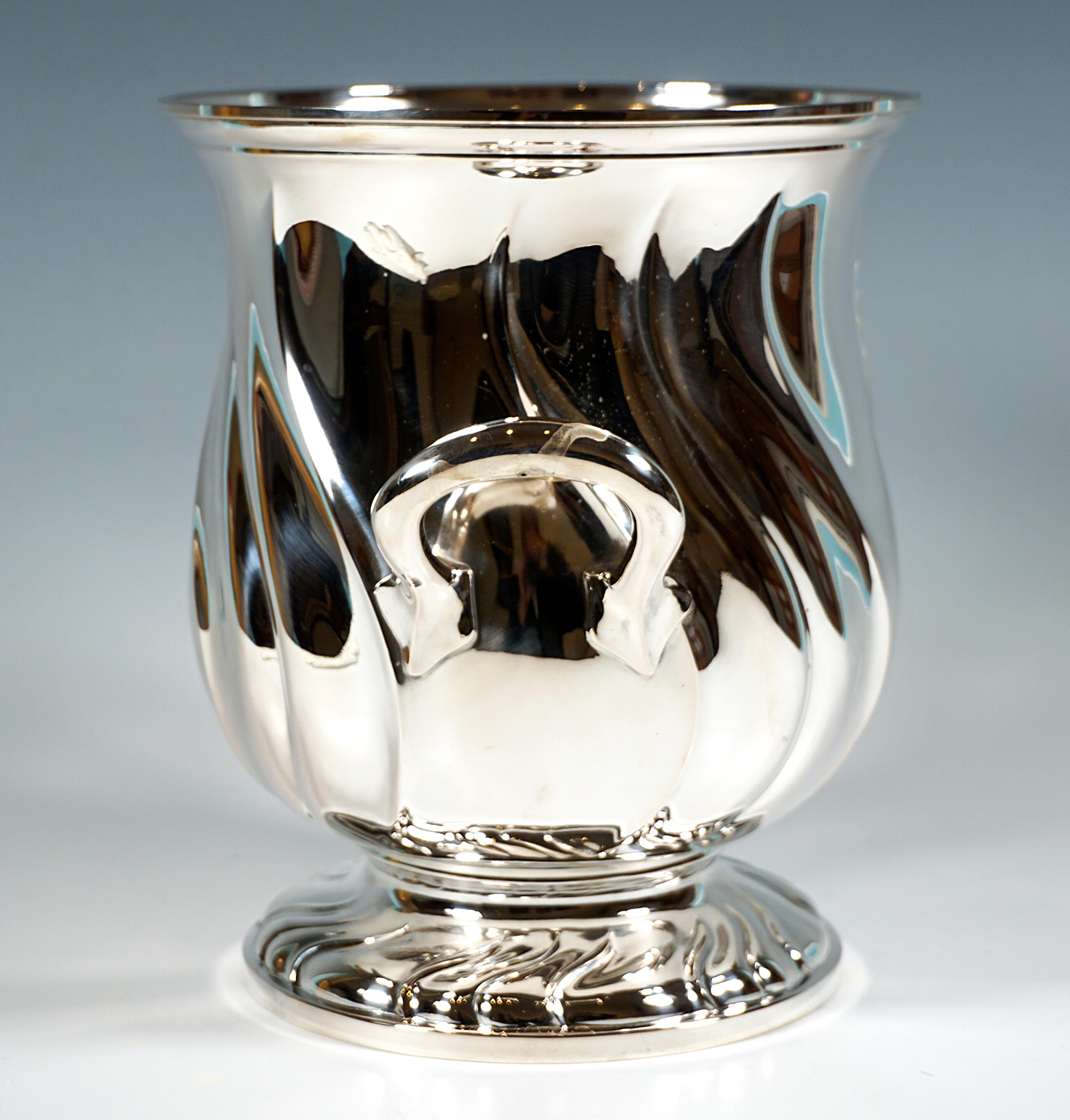 Elegant silver vessel in the shape of a tulip with a wide opening on a stepped stand, the wall and foot with curved triple folds, the rim profiled and turned outwards, two raised handles with a five-pointed finial in the lower, curved area.

-